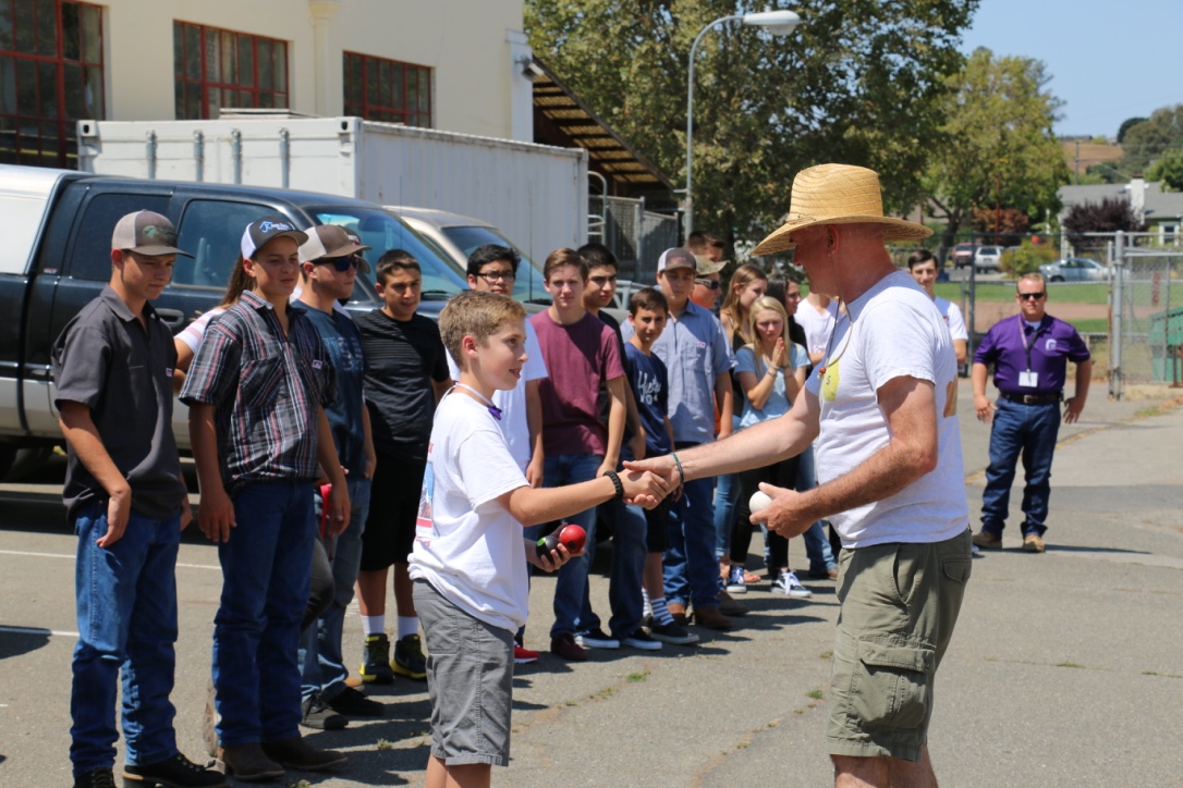 community members shaking hands with youth juggler